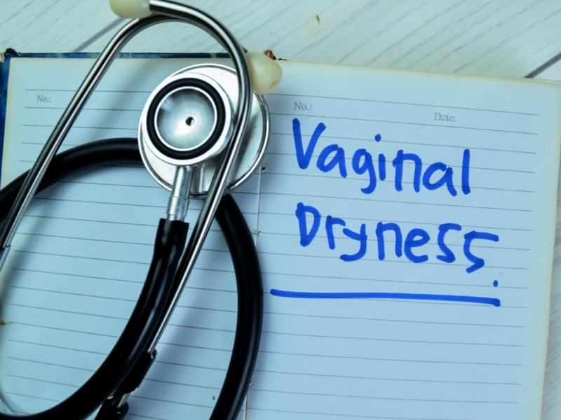 Vaginal dryness written on a medical notepad beside a stethoscope illustrating clinical causes and symptoms