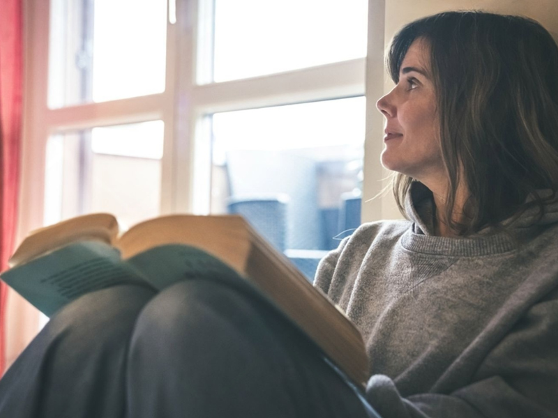 Woman in her forties reading by a window, reflecting on low libido and hormonal wellbeing