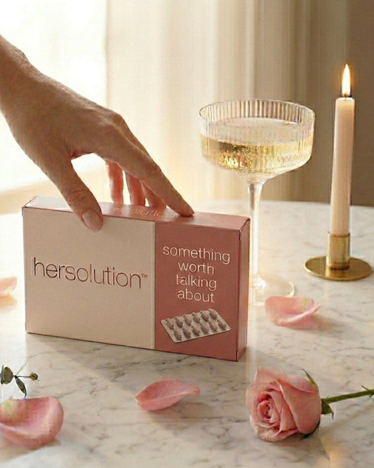 Hersolution product packaging on a marble surface with a hand - glass, and candle in the background