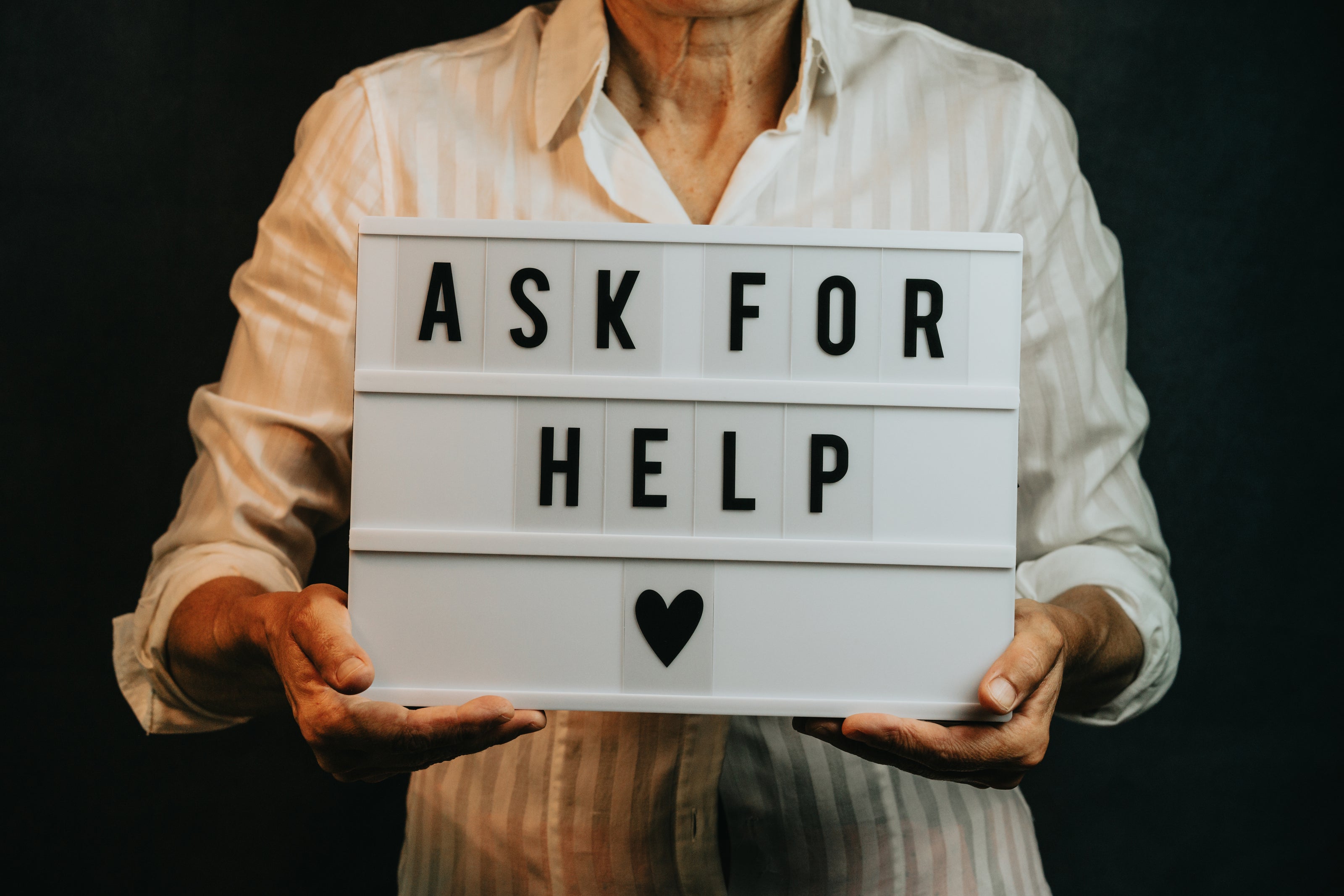 Man holding sign that says "Ask for Help"